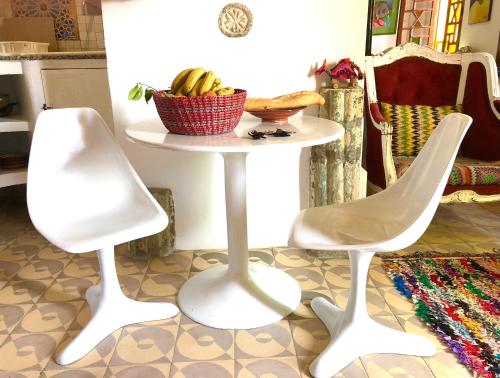 two white chairs and a table with a bowl of bananas at Dar 91 Essaouira in Essaouira