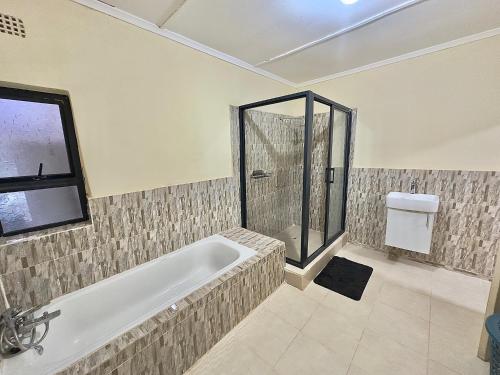 a bathroom with a bath tub and a shower at Chalala Apartment in Lusaka