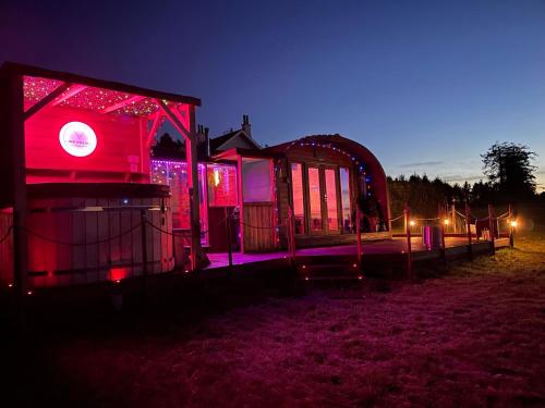 a building with red and purple lights at night at FINN VILLAGE – Loch Lomond Luxury Lodges with All Year-Round Hot Tubs and Gazebos in Glasgow