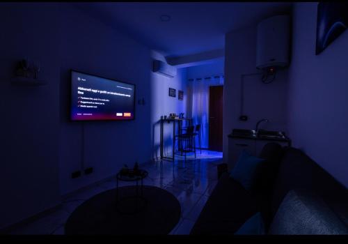 una sala de estar oscura con TV en la pared en SUITE CONCEPT ITALY, en Casoria