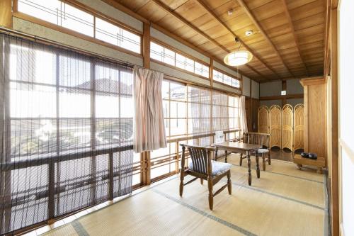 um quarto com uma mesa e cadeiras e janelas grandes em Ichimaru Ryokan - Vacation STAY 35990v em Tenkawa