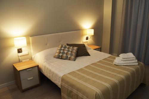 um quarto com uma cama grande e 2 candeeiros em Apartamenticos Plaza del Pilar I em Saragoça