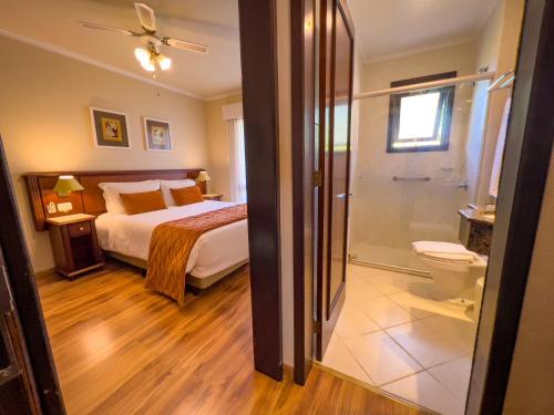 a bedroom with a bed and a bathroom with a toilet at Hotel Recanto da Serra in Gramado