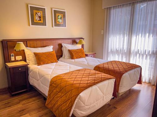 a hotel room with two beds and a window at Hotel Recanto da Serra in Gramado