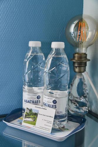 two bottles of water on a tray next to a light at Chambres D’hôtes Any-Jean Louis à Mios in Mios