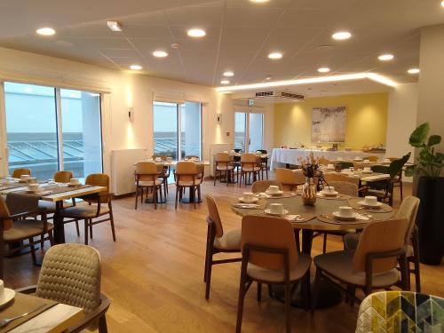 a dining room with tables and chairs and windows at Domitys L'Ellipse in Paris
