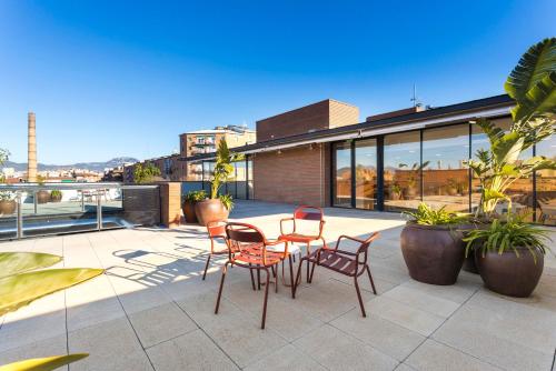 eine Terrasse mit Stühlen und Tischen auf einem Gebäude in der Unterkunft Hotel Terrassa Confort in Terrassa