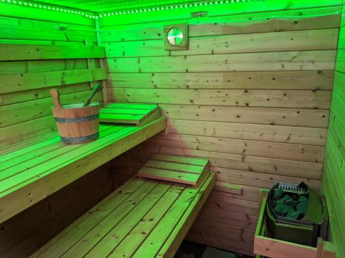 eine Holzsauna mit Eimer und grünem Licht in der Unterkunft Holiday house Vedle in Desná