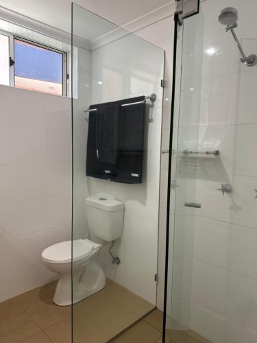 a bathroom with a toilet and a tv on the wall at 1 bedroom apartment opposite the beach in Cronulla
