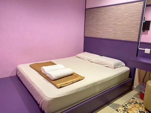 a purple room with a bed with towels on it at Best Hotel in Skudai