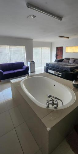 a large white bath tub in a room with a bed at Peace and Tranquility in Cape Town
