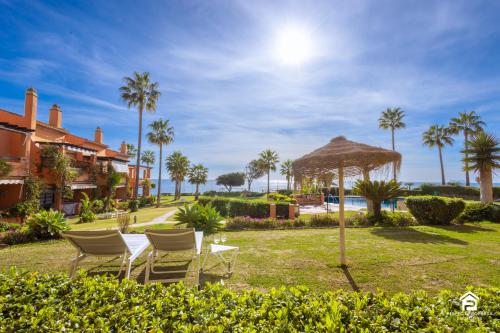 een groep stoelen en een tafel en een paraplu bij Apartment Los Molinos on the beachfront with pool in Estepona