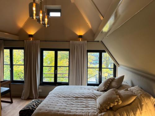 a bedroom with a large bed in a room with windows at Townhouse 't Raap in Amsterdam