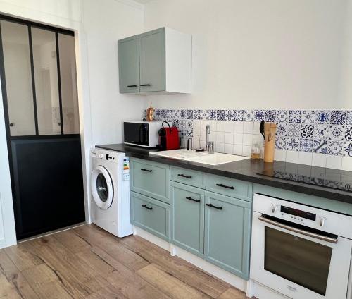 cocina con armarios azules, lavadora y secadora en Spacieux T2 idéalement placé, en Toulouse