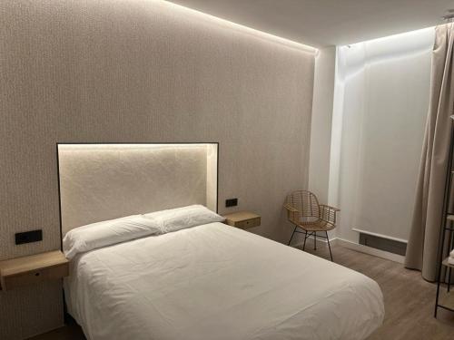 um quarto com uma cama branca e uma cadeira em Demetrio By Alma Suites em Valência