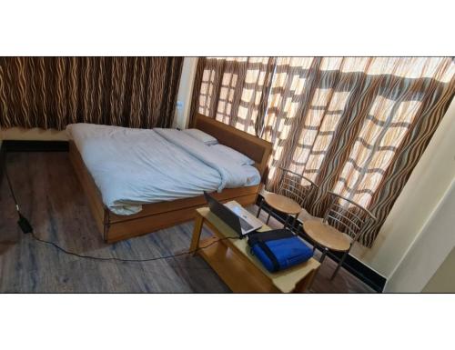 a bedroom with a bed and two chairs and a window at Hotel Basant Inn, Srinagar in Srinagar