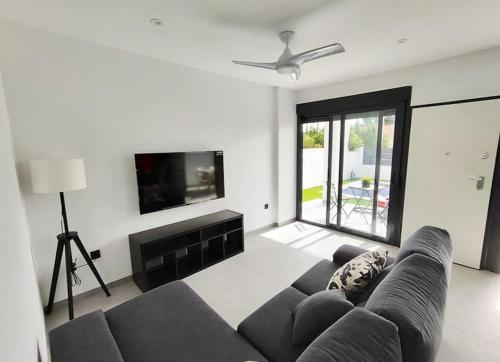 sala de estar con sofá y TV de pantalla plana en Maison neuve moderne en Los Baños
