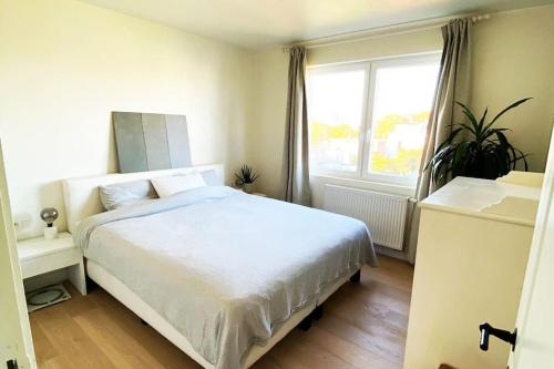 1 dormitorio con cama blanca y ventana en Classy flat with awesome view and great location! en Amberes
