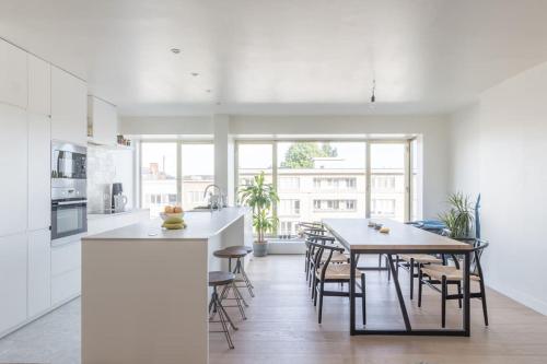a white kitchen with a table and chairs in it at Classy flat with awesome view and great location! in Antwerp
