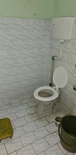 a bathroom with a toilet and a tiled floor at Hotel HillView, Junagadh in Junagadh