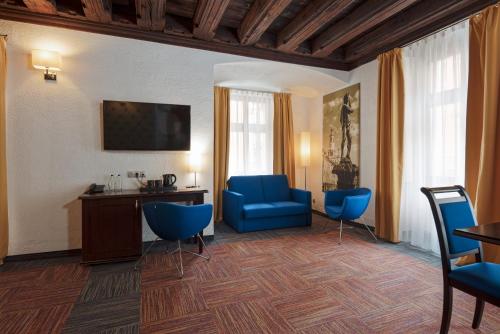 une chambre d'hôtel avec des chaises bleues, un bureau et une chambre dans l'établissement Palazzo Rosso Old Town, à Poznań