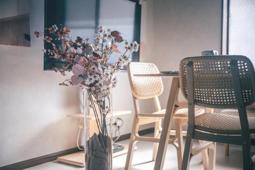 a table with chairs and a vase with flowers at Japandi House Haneda in Tokyo