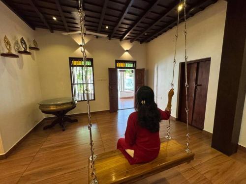 une femme assise sur une balançoire dans une pièce dans l'établissement Heritage Homestay Paravur, à Paravūr