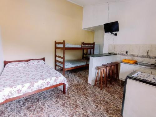 a bedroom with a bed and a kitchen with a counter at Diva Surf Quartos in Ubatuba