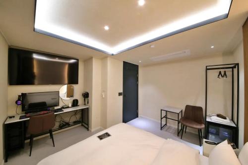 um quarto de hotel com uma cama, uma secretária e uma televisão em Hotel141 em Daejeon