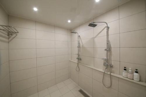 a white tiled bathroom with a shower in it at Hotel141 in Daejeon