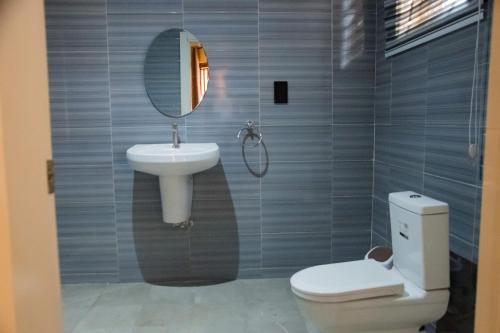 ein Badezimmer mit einem Waschbecken, einem WC und einem Spiegel in der Unterkunft Agya Complex in Baatsona