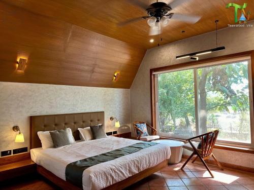 a bedroom with a large bed and a large window at Luxurious 3BHK W//Pool Teakwood Villa By Gemstone Hospitality in Alibag
