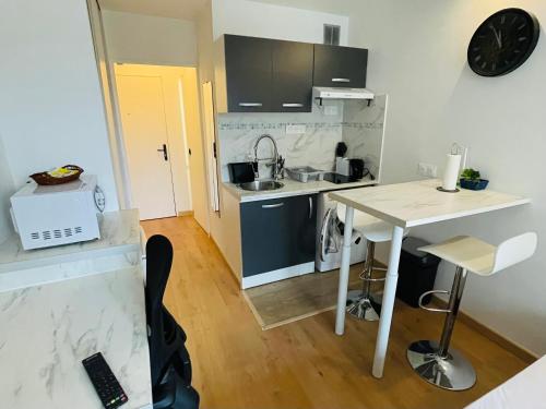 une petite cuisine avec une table et un évier dans l'établissement Exclusive Private Apartment by Warilco - Pleyel 25 m2 - À 1 minute de la station métro Carrefour Pleyel, à Saint-Denis