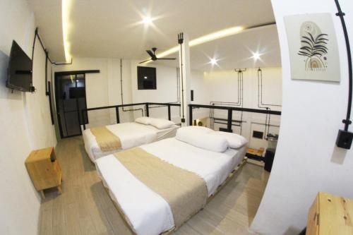 1 dormitorio con 2 camas y TV. en KLAB House - Guest House, en Yogyakarta