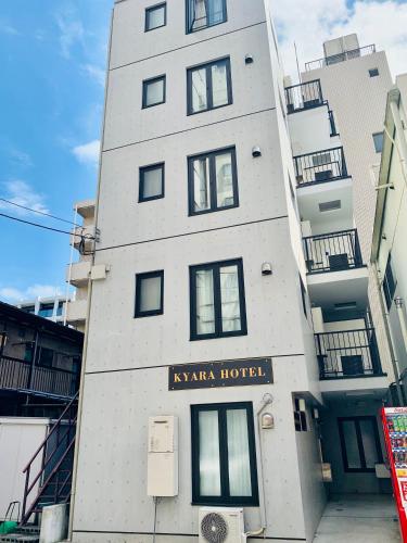 a tall white building with a sign on it at KYARA HOTEL 亀戸a in Tokyo