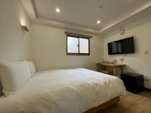 台北的住宿－宏洲旅社HZ Hotel，卧室配有白色的床和平面电视。