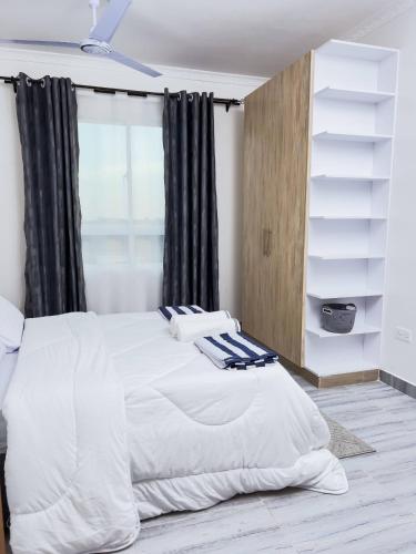 a white bed in a bedroom with a window at Semo's Siloam apartments in Mombasa
