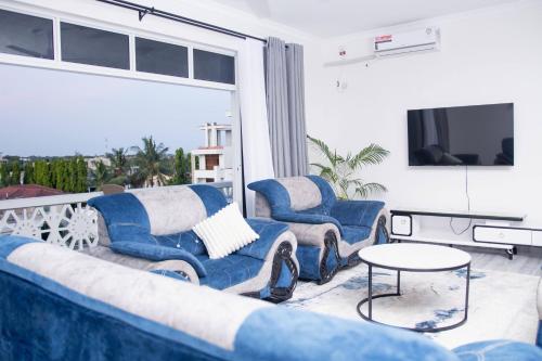 a living room with two blue chairs and a tv at Semo's Siloam apartments in Mombasa