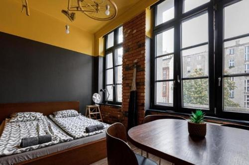 a bedroom with a bed and a table and windows at Golden Apartments Wrocław&K28 in Wrocław