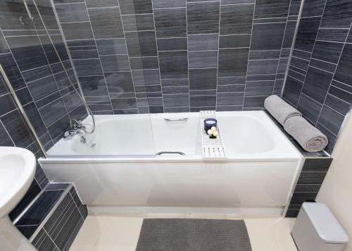 a bathroom with a white tub and a sink at Stay at Waltz Gate in Horley