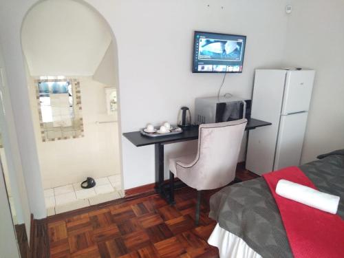 a small room with a desk and a refrigerator at Comrades Oasis Guest House in Pietermaritzburg