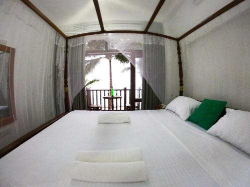 a large white bed in a room with a window at Asa Bay Beach Resort in Talpe