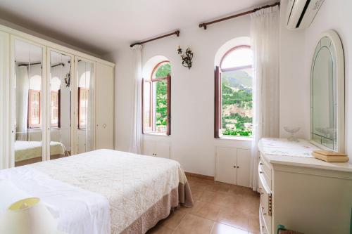 een witte slaapkamer met een bed en 2 ramen bij Casa Danira - Positano in Positano