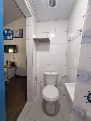 a white bathroom with a toilet and a bath tub at SUÍTES Caminho do Mar in Abraão