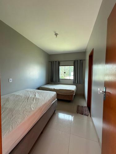 sypialnia z 2 łóżkami i oknem w obiekcie Rancho Coqueiros w mieście Abadiânia
