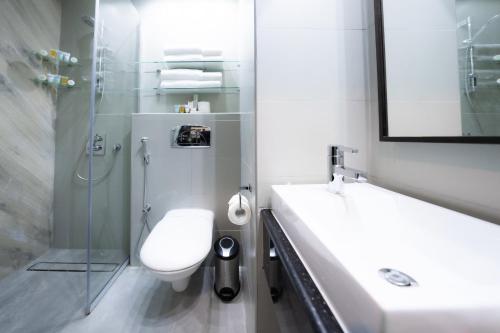 a bathroom with a toilet and a sink and a shower at Ramada Encore Doha by Wyndham in Doha