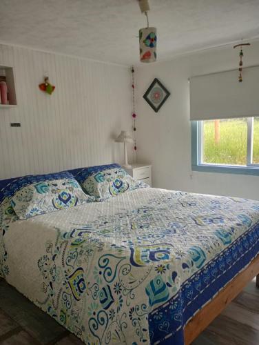 1 dormitorio con 1 cama con edredón azul y blanco en Habitaciones Punto Medio 1, en Puerto Varas