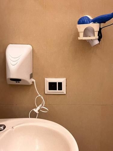 a bathroom with a toilet with a blow dryer on the wall at Centrally located, big home in Kolkata