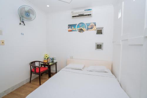 a white bedroom with a bed and a table at Triệu Vũ Hotel & Apartment in Buon Ma Thuot