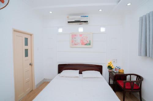 a white bedroom with a bed and a chair at Triệu Vũ Hotel & Apartment in Buon Ma Thuot